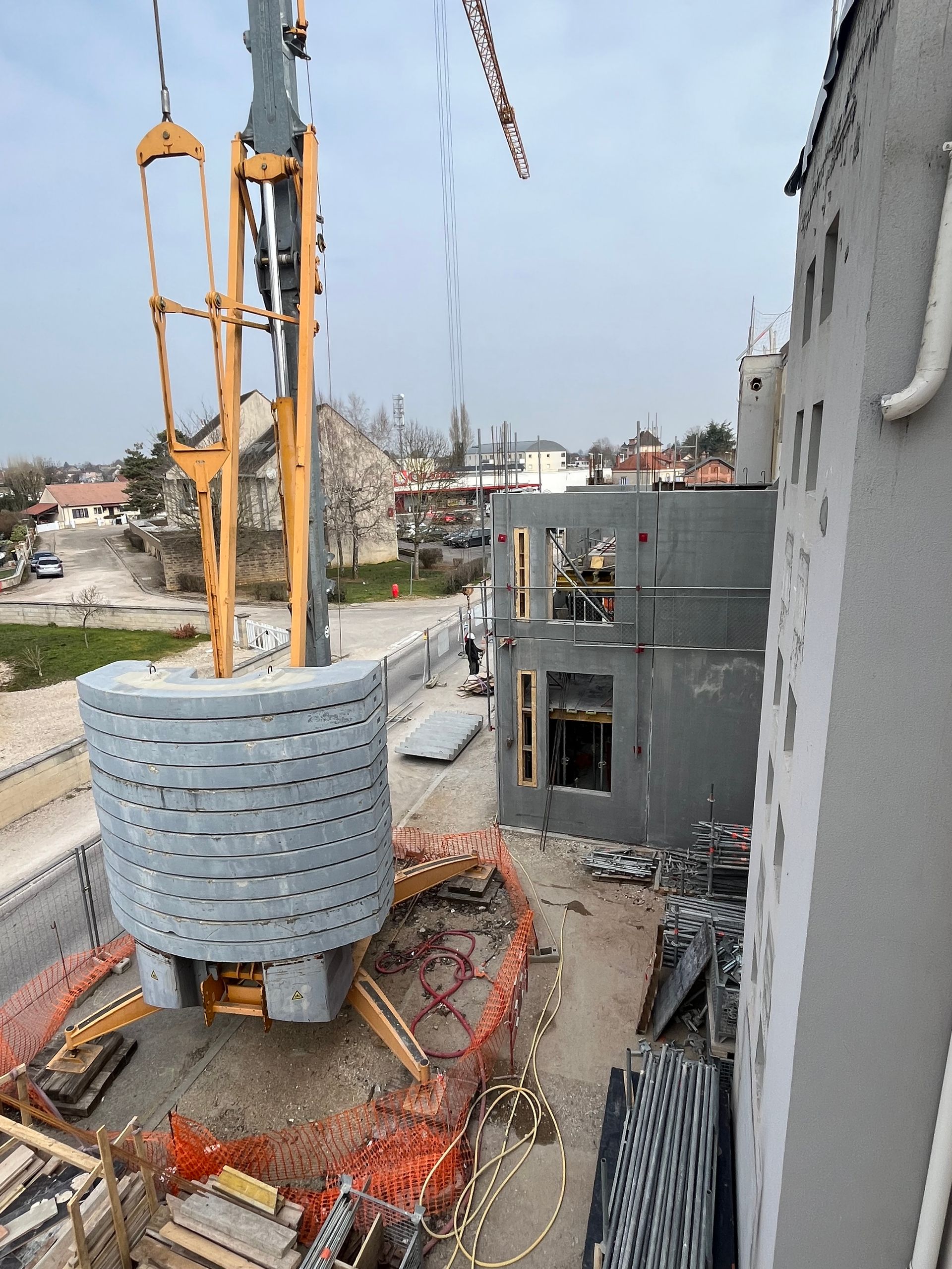 Structure en béton avec des armatures en acier visibles, en cours de construction. Des échafaudages et des barres de renforcement sont visibles.
