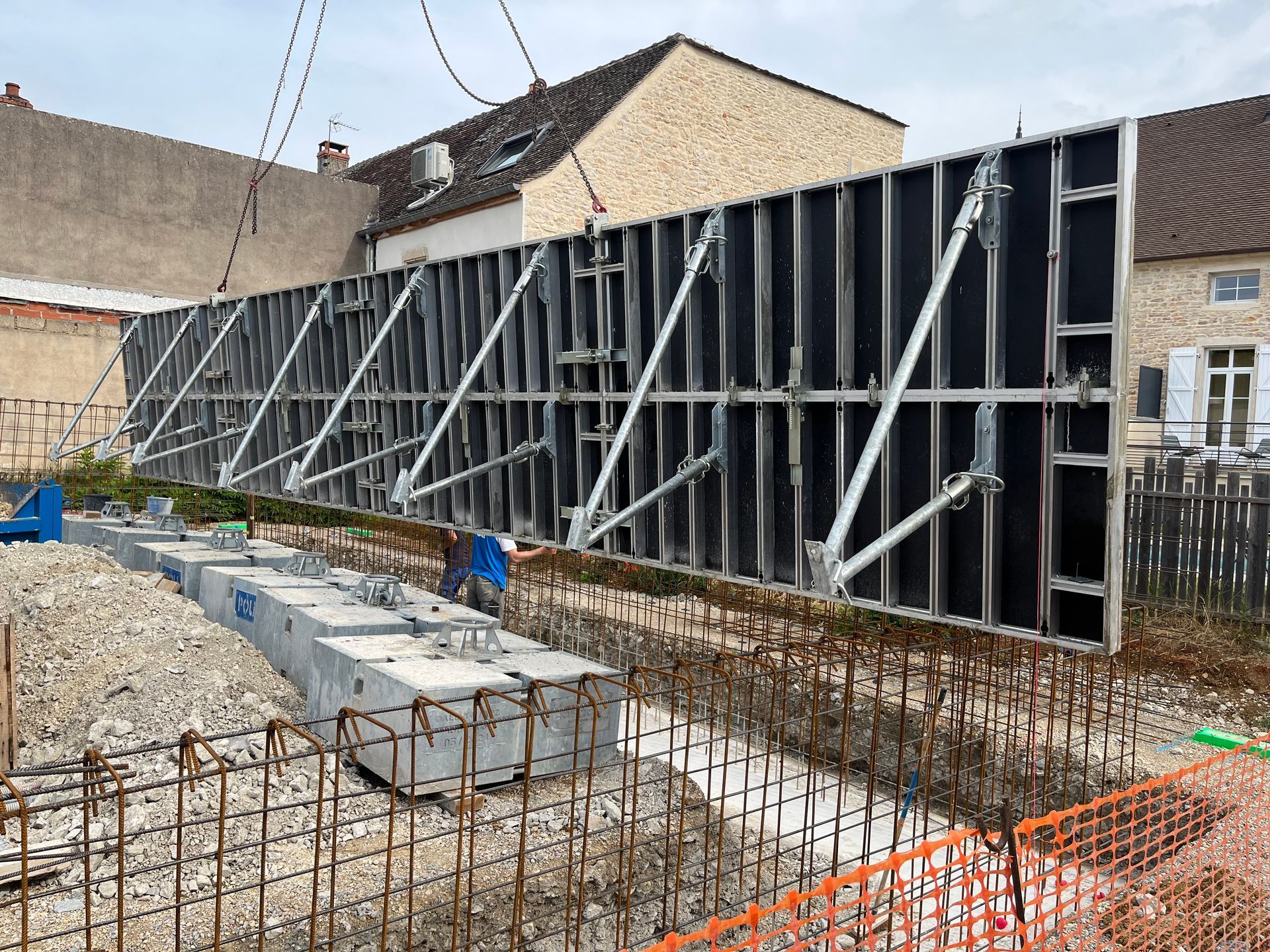 Structure en béton avec des armatures en acier visibles, en cours de construction. Des échafaudages et des barres de renforcement sont visibles.