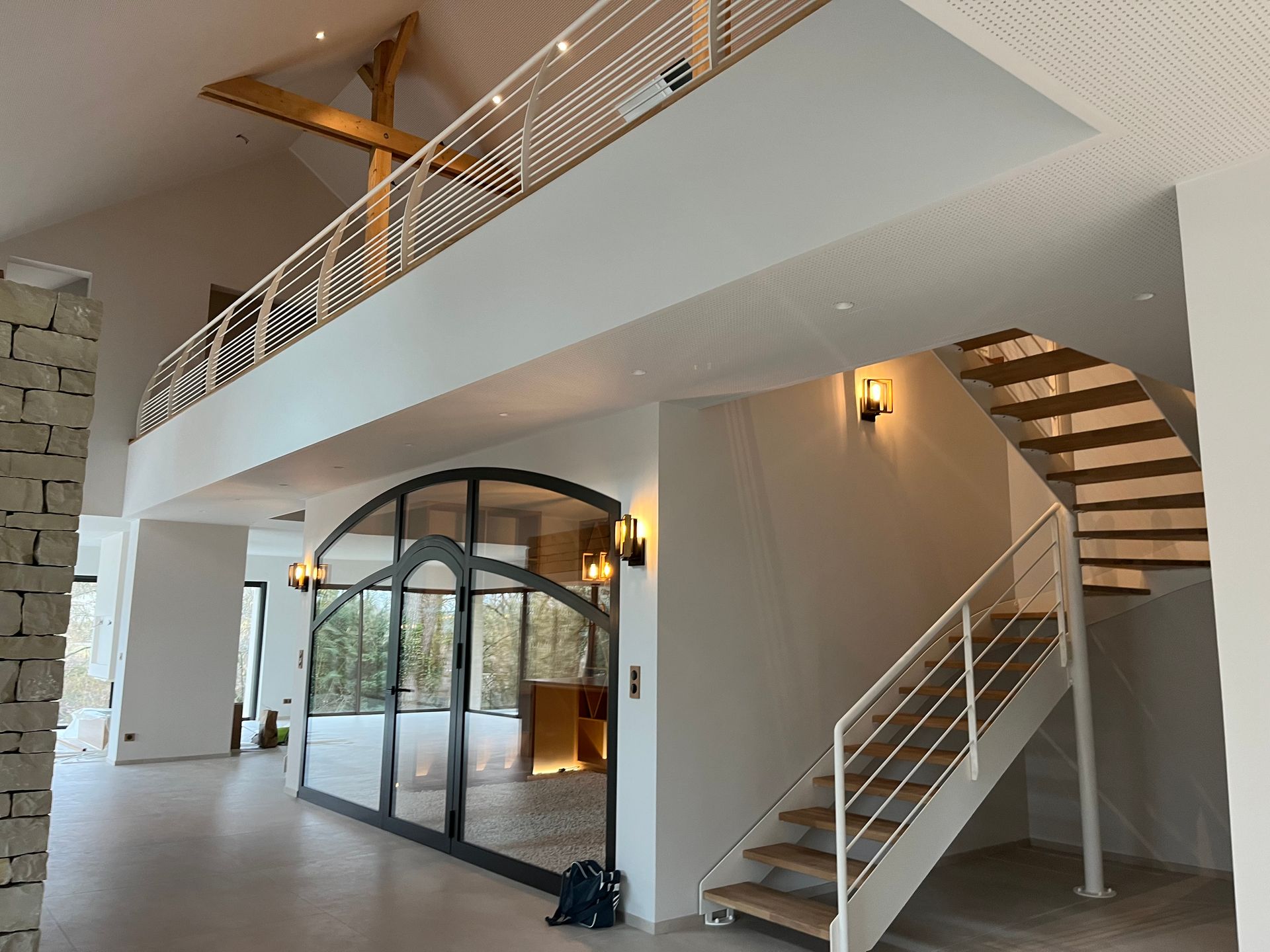 Intérieur d'un bâtiment moderne avec un escalier en colimaçon et des structures en métal. La pièce est bien éclairée et semble être un espace de vie ou de travail contemporain.