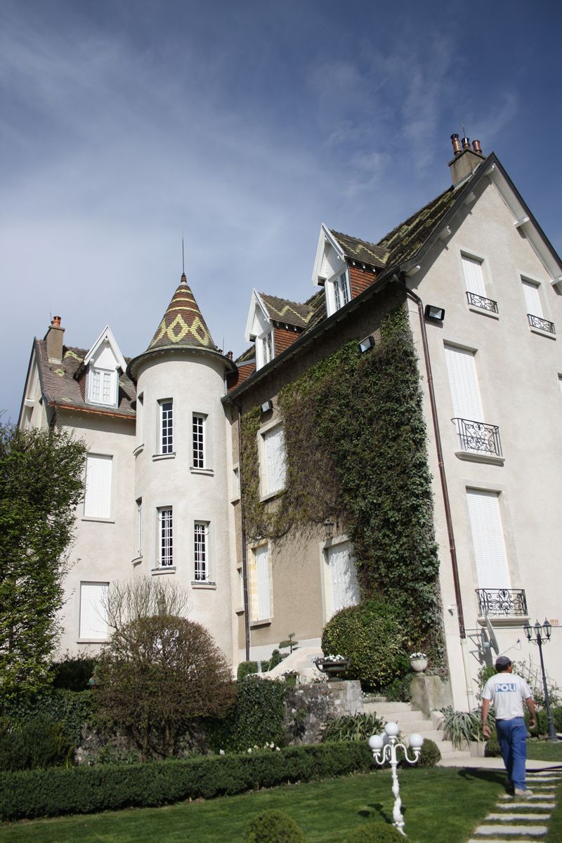 Bâtiment ancien avec une tour et de la végétation grimpante.