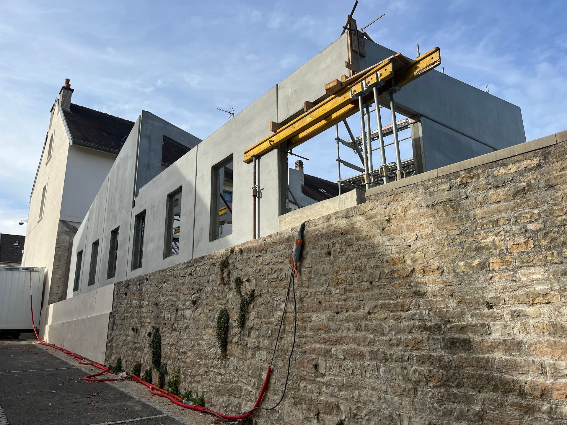 Construction d'une extension de maison au-dessus d'un mur en pierre en béton.