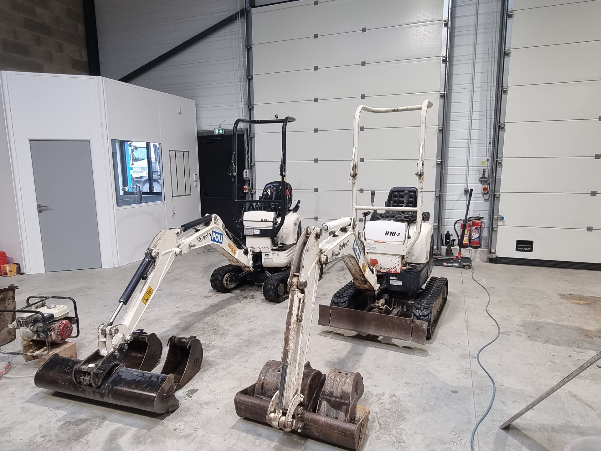 Deux mini pelles de chantiers de couleur blanche dans l'entrepôt.