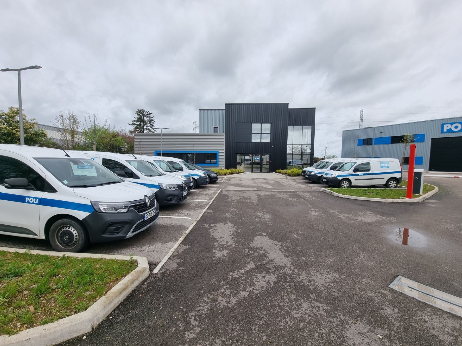 Parking avec des véhicules de police et un bâtiment industriel en arrière-plan.