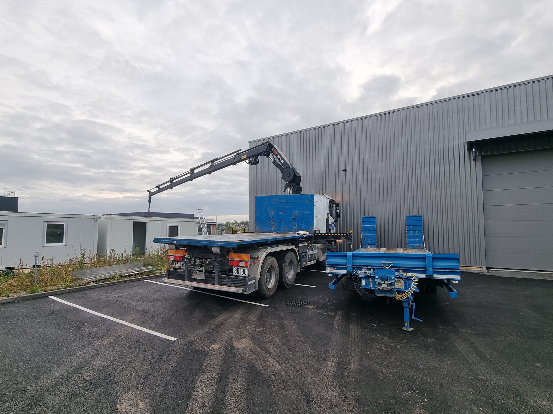 Camion-grue devant un entrepôt.