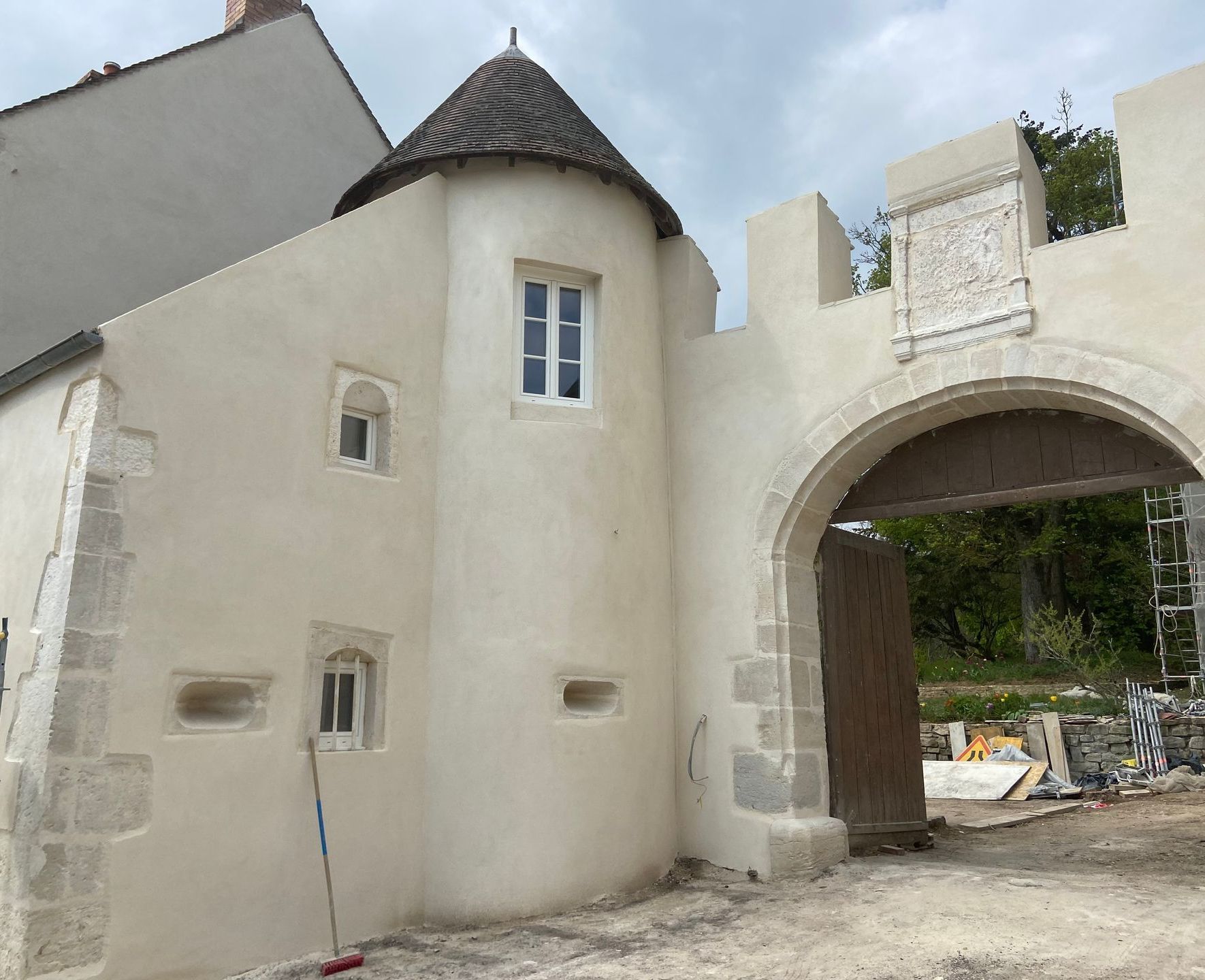 Mur en pierre ancienne avec des détails de construction et un clochet d'Eglise en fond.