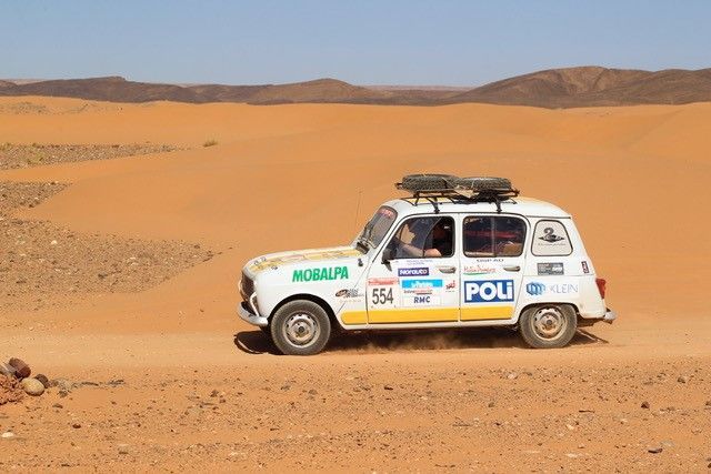 Renault 4L blanche sponsorisée Poli traversant le désert lors du 4L Trophy