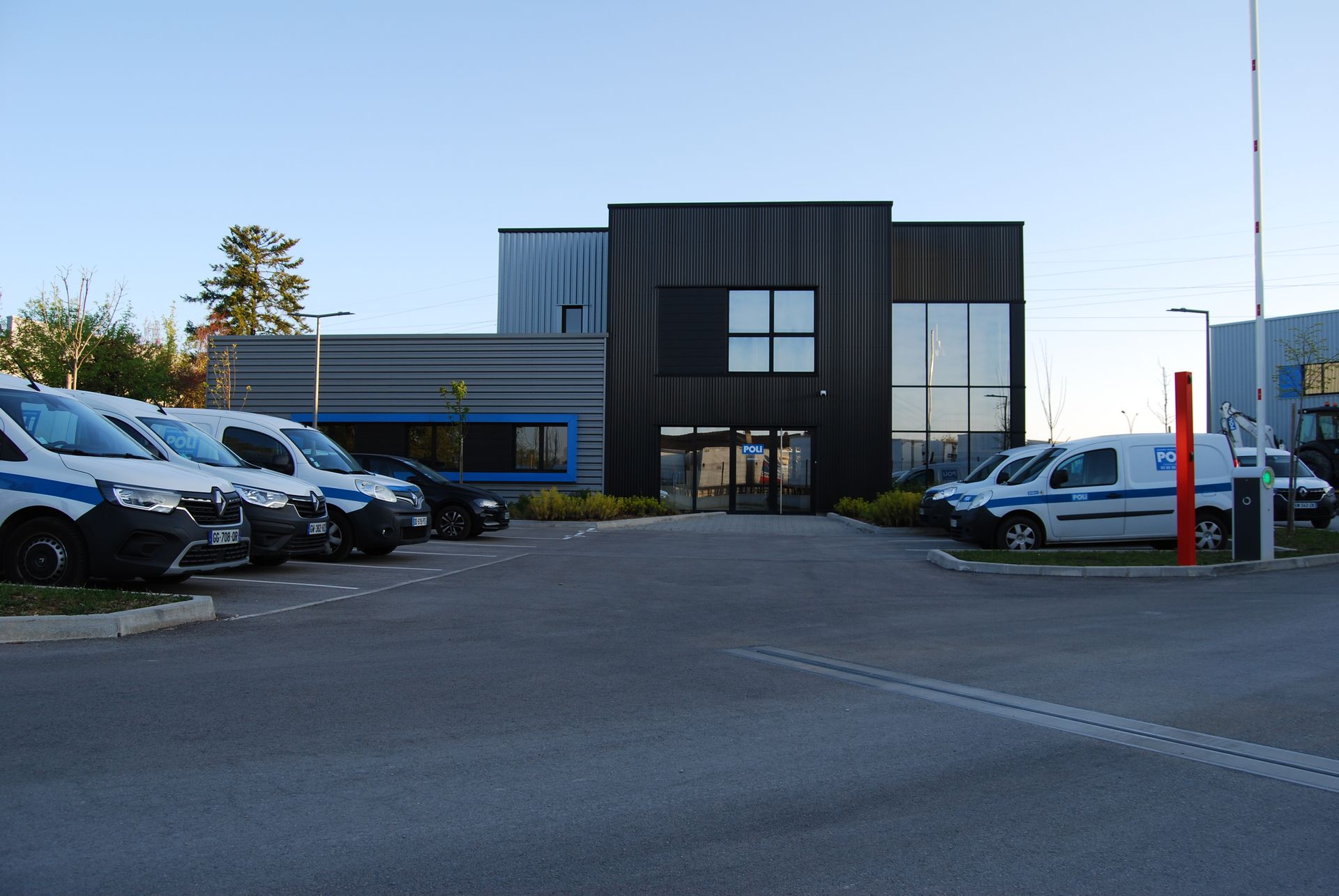 Bâtiment industriel moderne avec parking et véhicules garés.