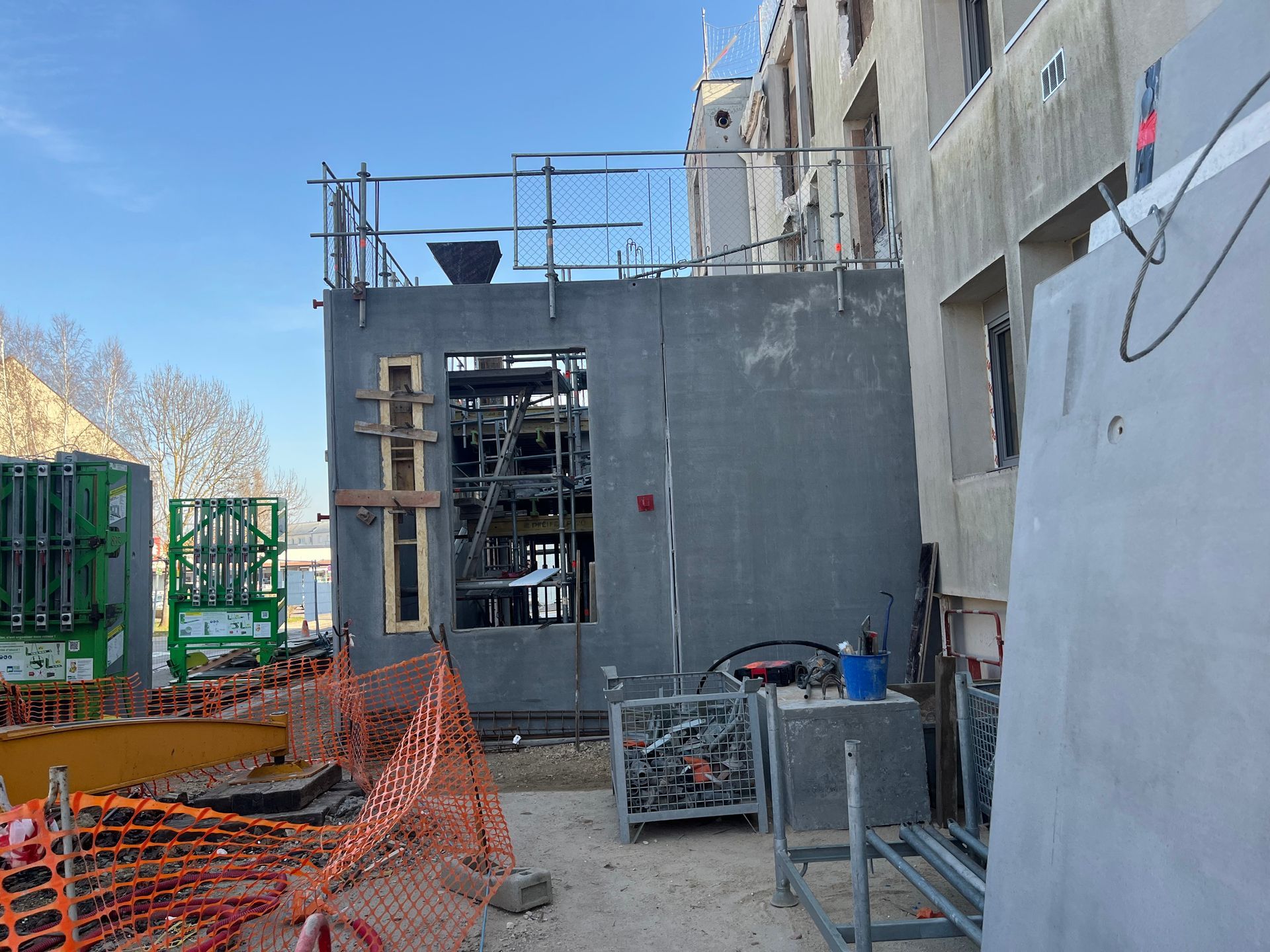 Bâtiment en construction avec échafaudages et matériaux de construction.