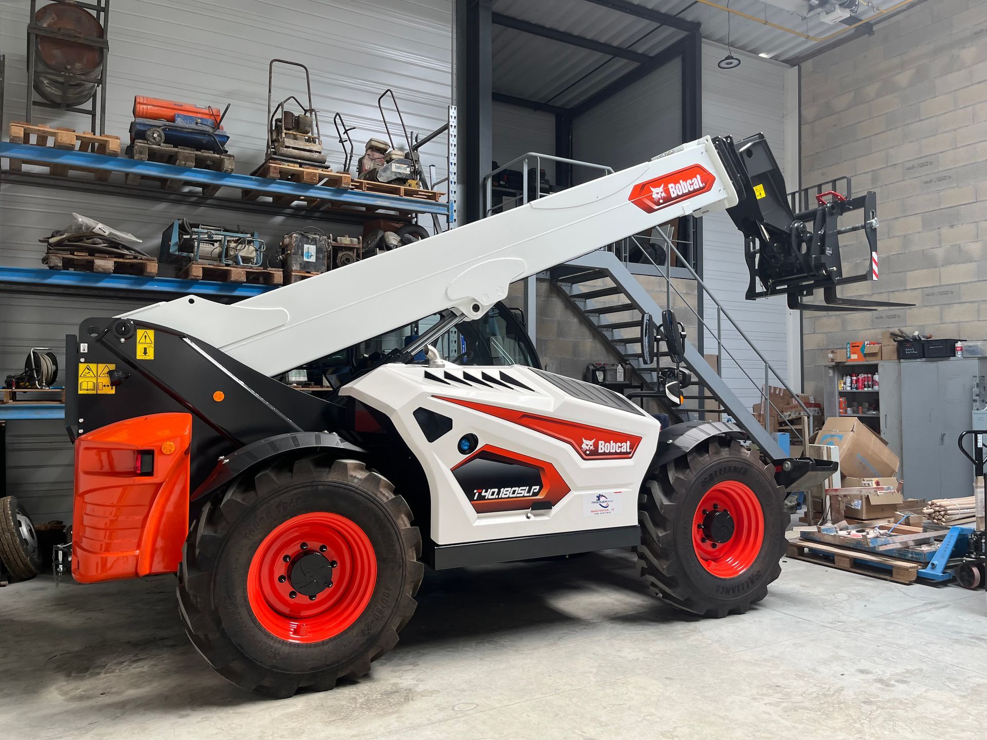 Manitou blanc avec un bras élévateur pour charger et décharger des marchandises.