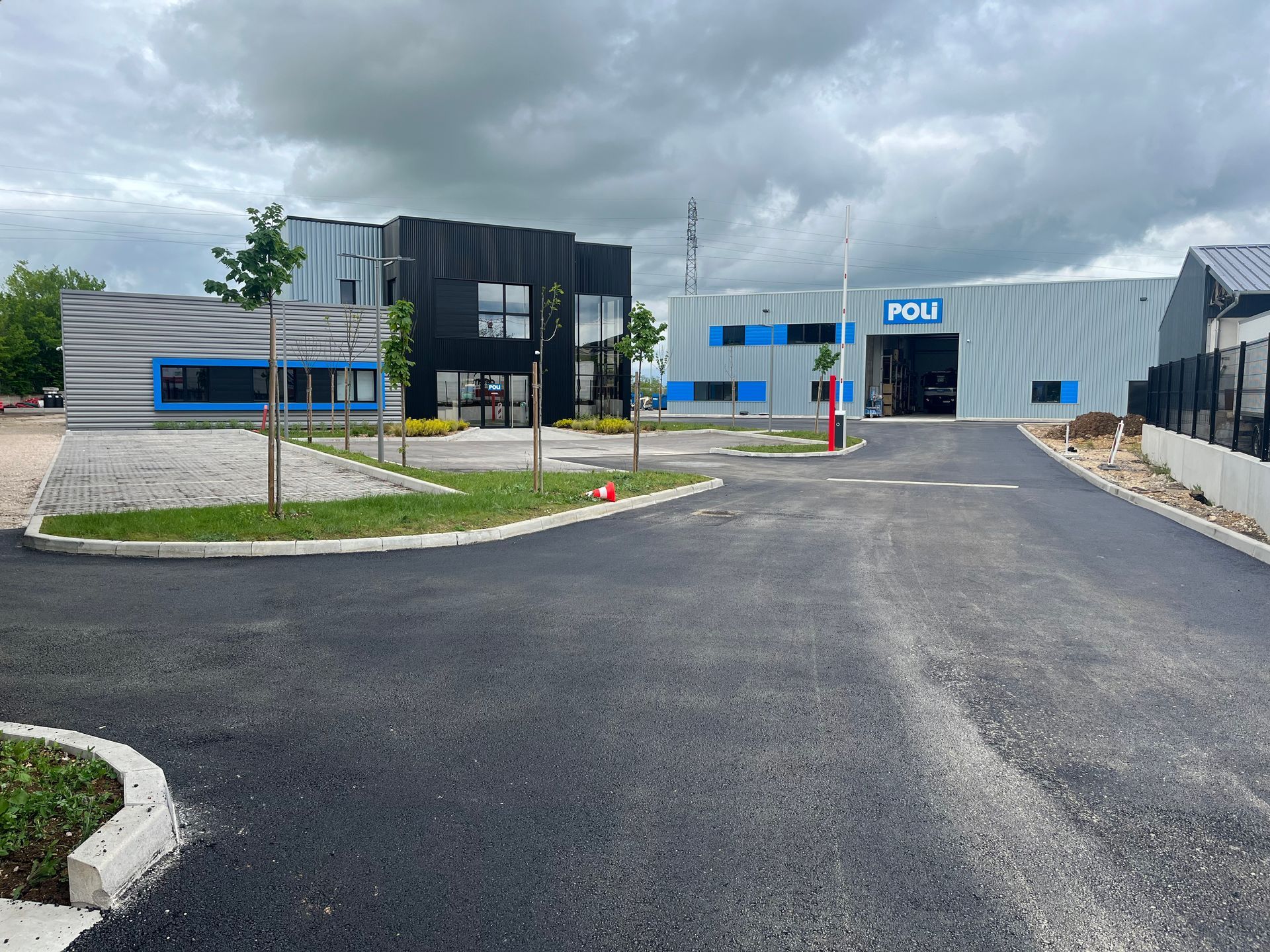Bâtiment industriel moderne avec parking vide sous un ciel nuageux.