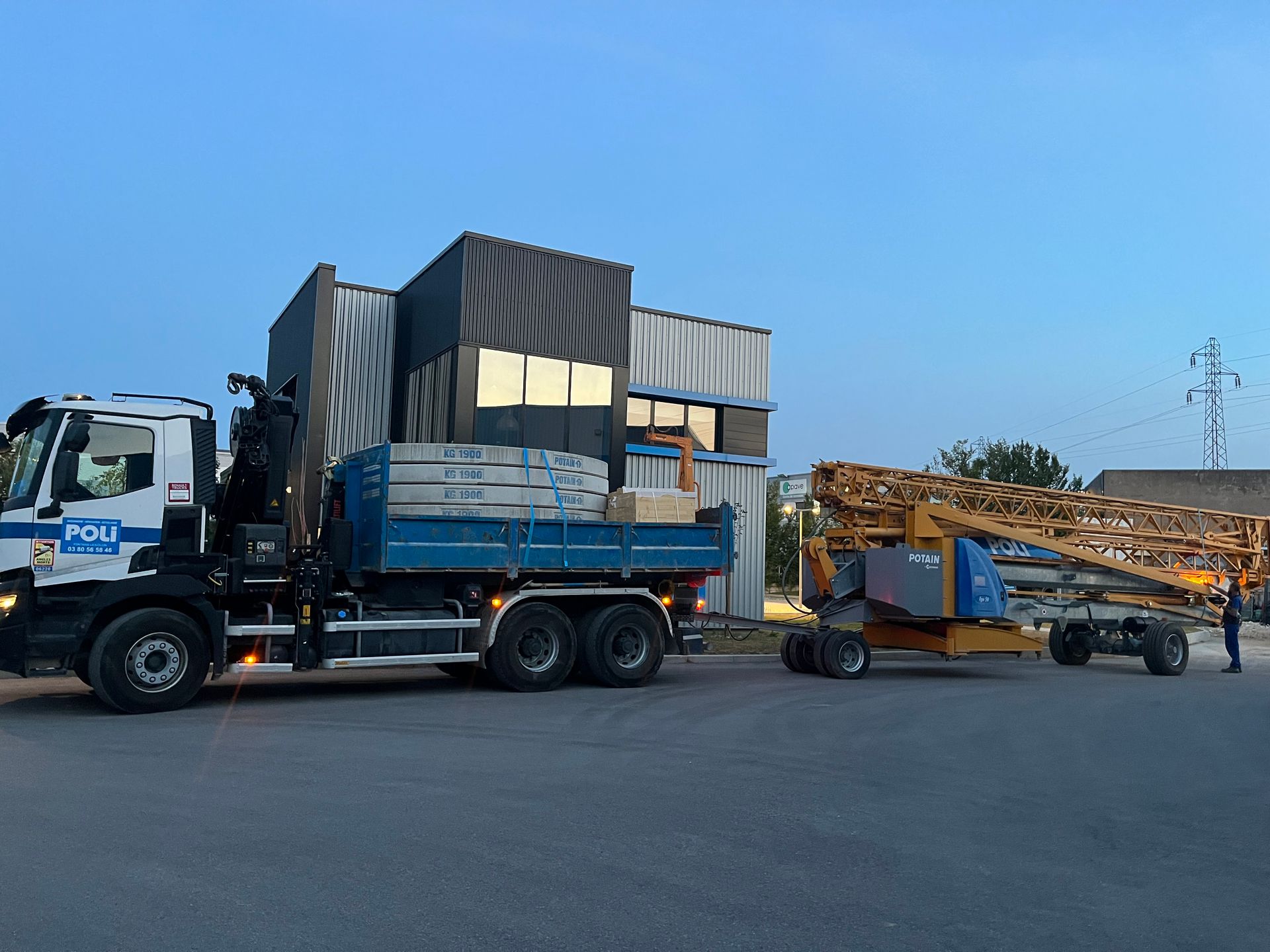 Camion-grue avec la remorque chargée de matériaux en train de tracter une grue plié jaune.