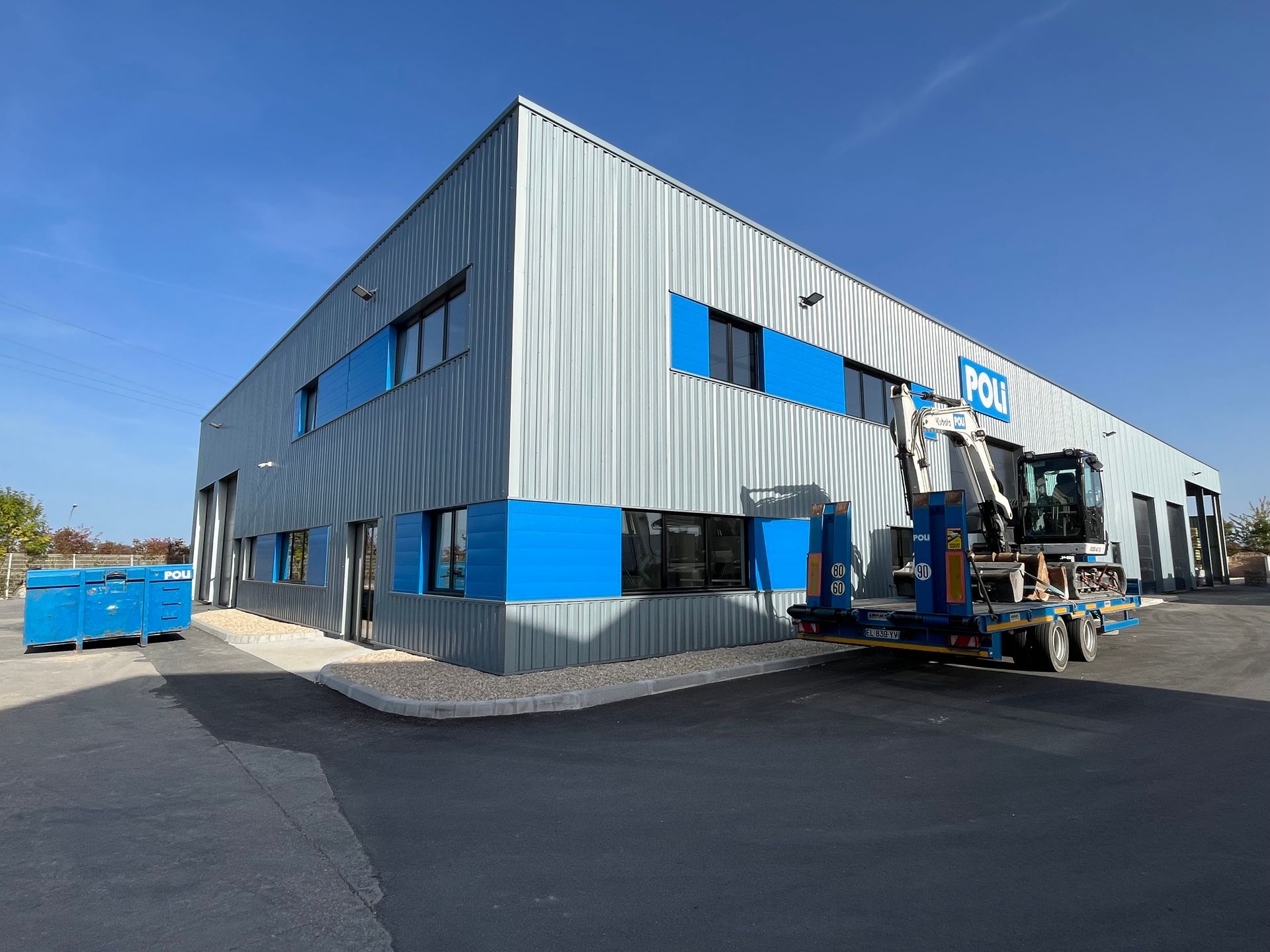 Bâtiment industriel avec une façade métallique et des fenêtres bleues.