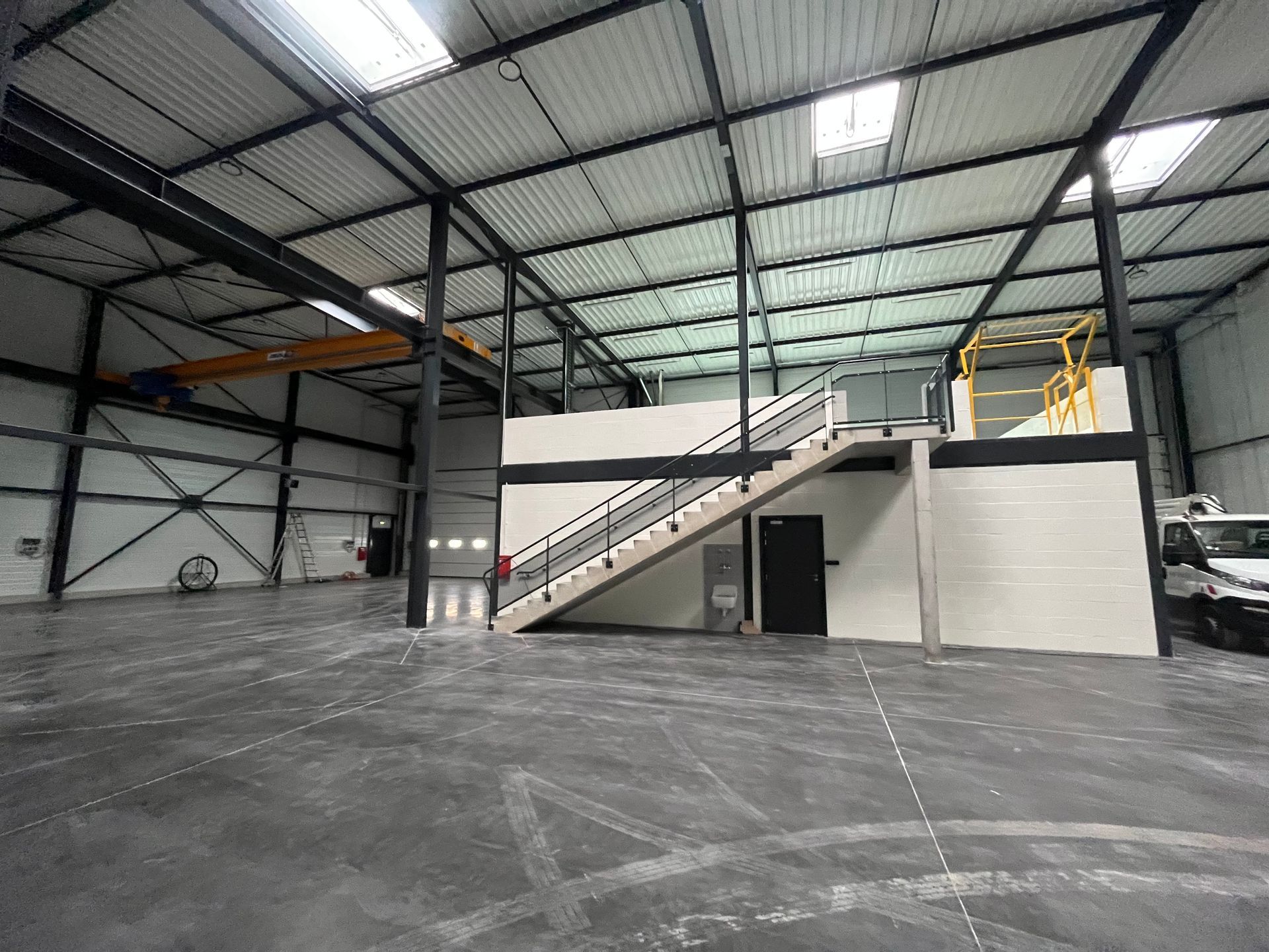  Intérieur d'un bâtiment industriel moderne avec des structures en métal et des escaliers. Des échafaudages sont visibles pour soutenir la structure.