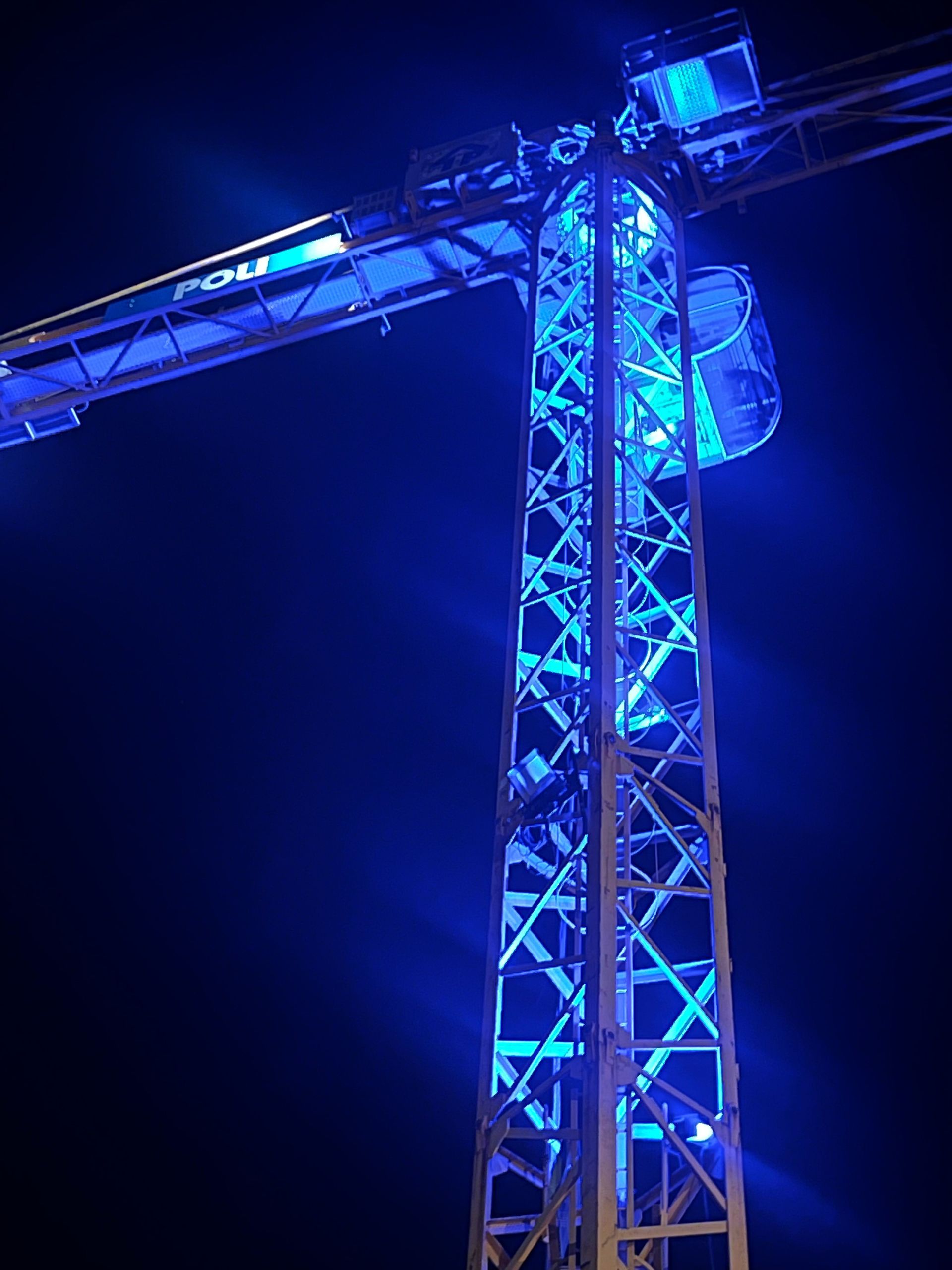 Grue illuminée en bleu, probablement une tour ou une attraction.