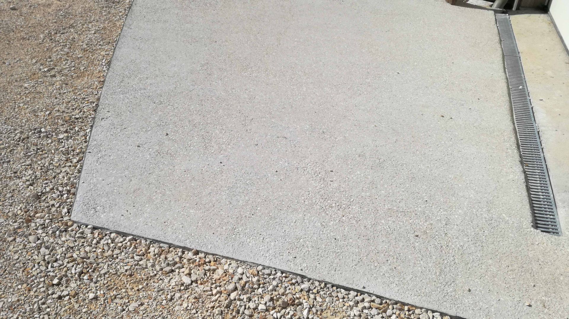 Terrasse en béton entourée d'une bordure de gravier ; drainage métallique.