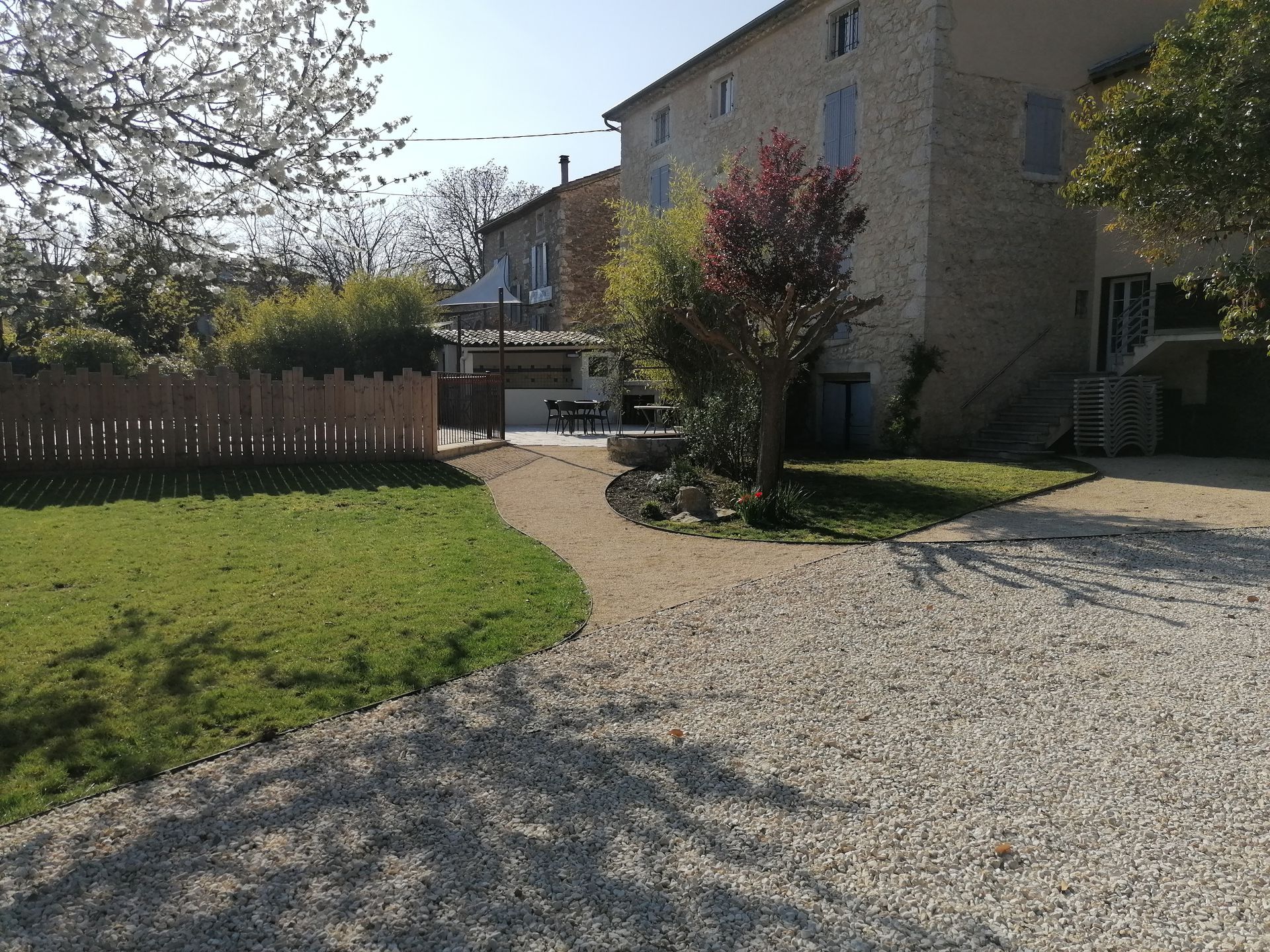 Demeure en pierre dotée d'une allée gravillonnée, d'un jardin en gazon et d'une clôture en bois.