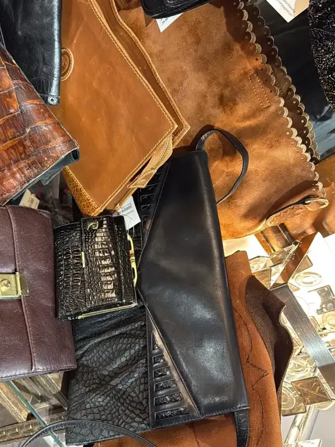 Montón de artículos de cuero en varios tonos de marrón y negro. Incluye bolsos, carteras y artículos de cuero.