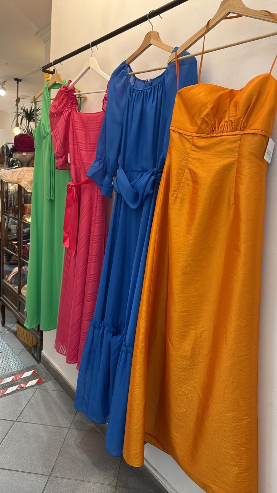 Maniquí con un abrigo largo gris en una tienda con papel tapiz floral y un espejo.