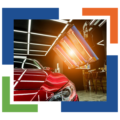 Un coche rojo está siendo tratado con una luz en un garaje.