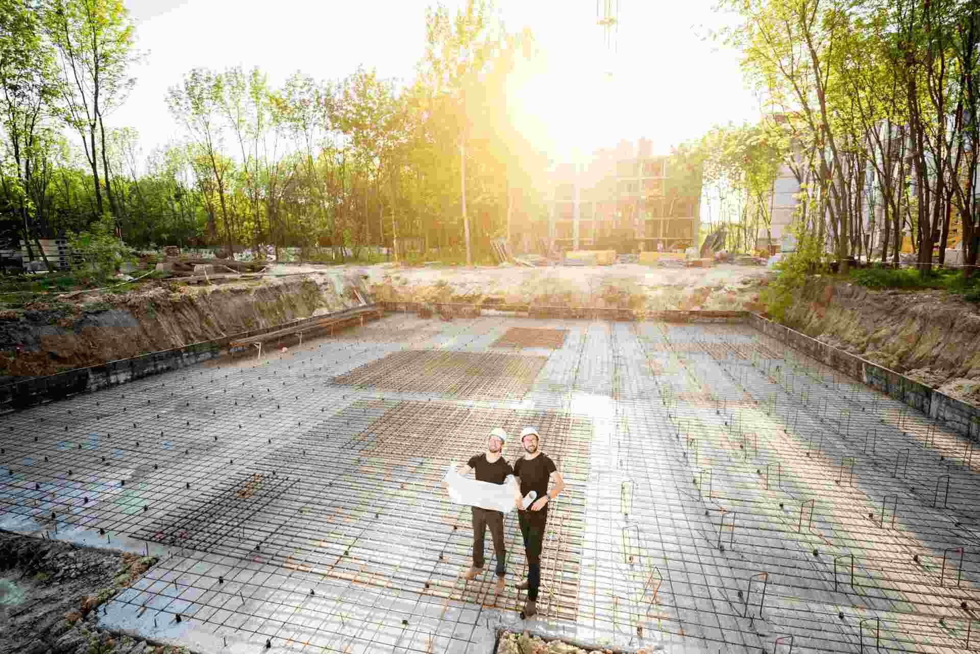 Deux experts contrôlent les fondations d'un chantier, plan à la main