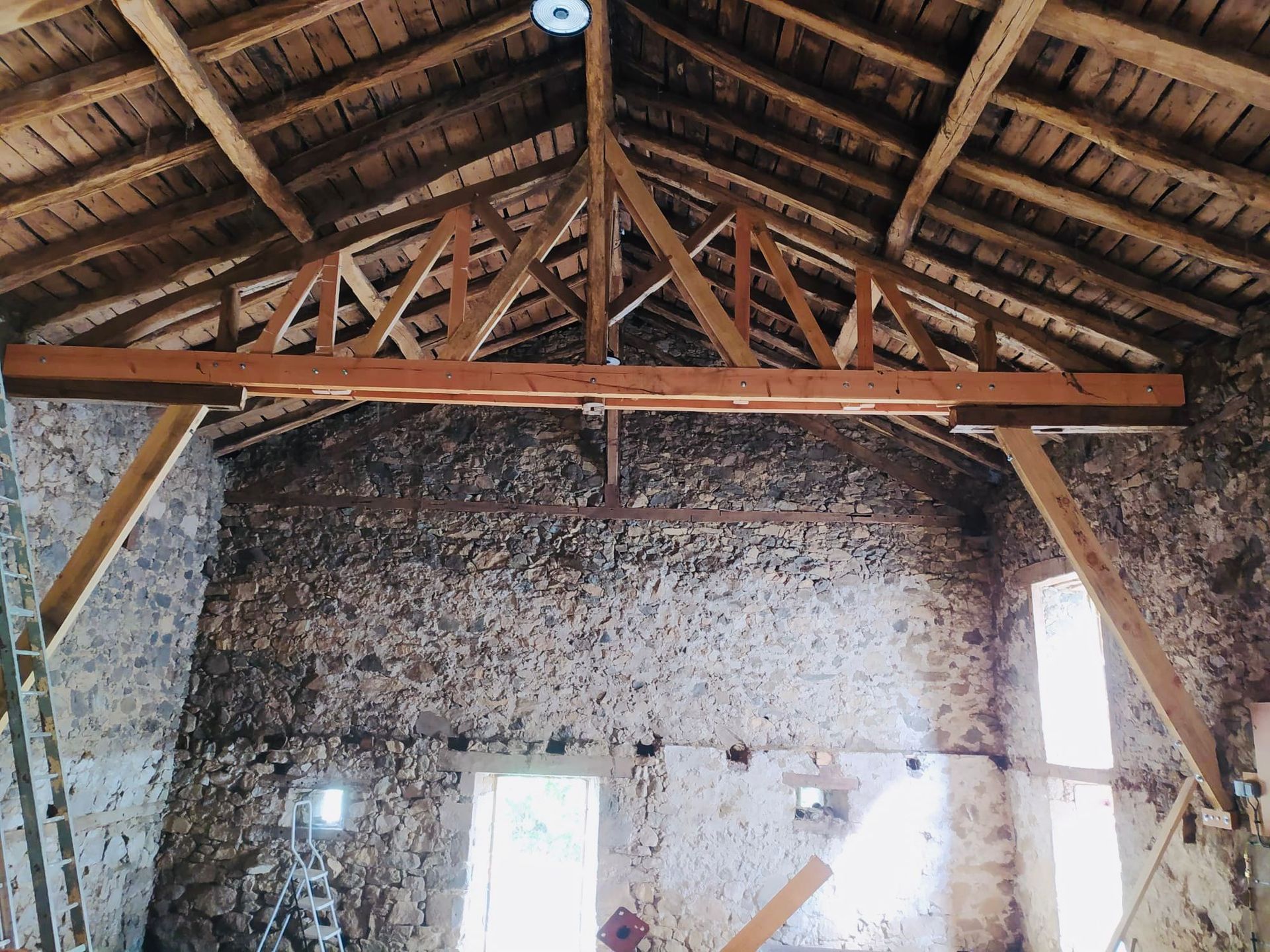 Intérieur d'une grange rustique en bois avec charpente apparente.