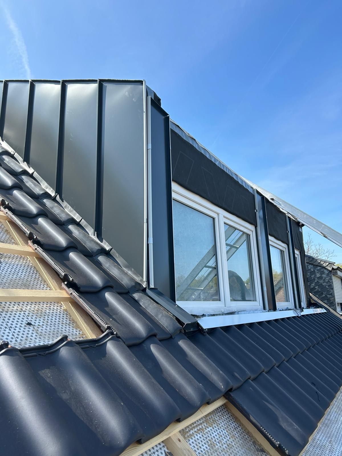 Ein Mann sitzt auf einem Dach und hält einen Ziegelstein