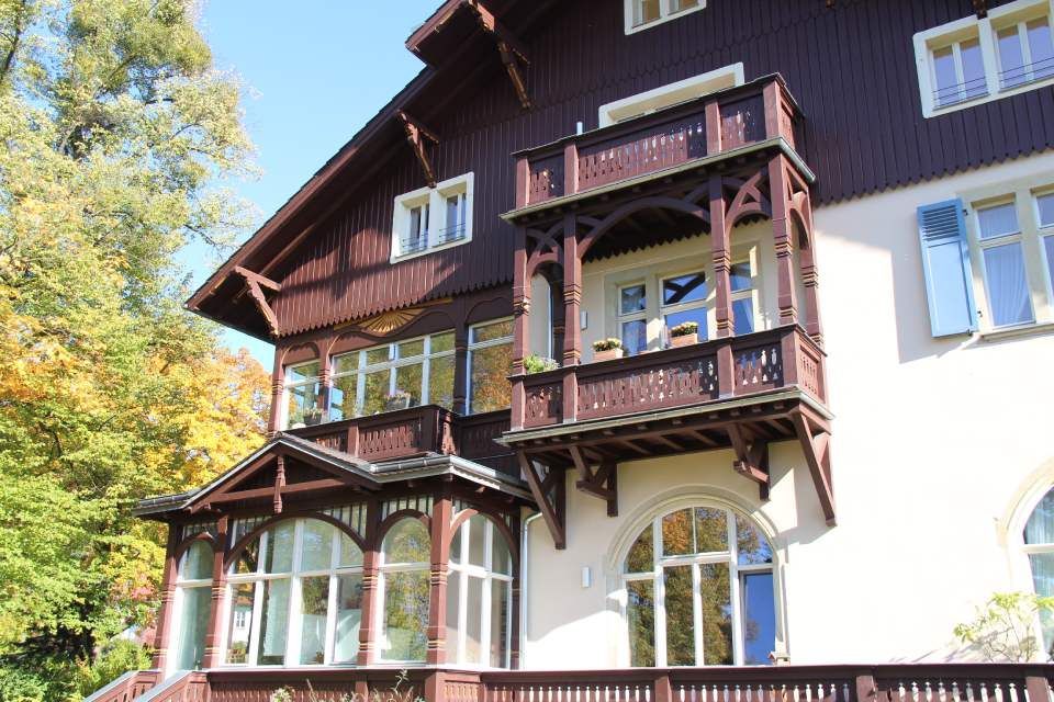 Haus im Landvillen-Stil mit zwei Holzbalkonen und einer Holzveranda