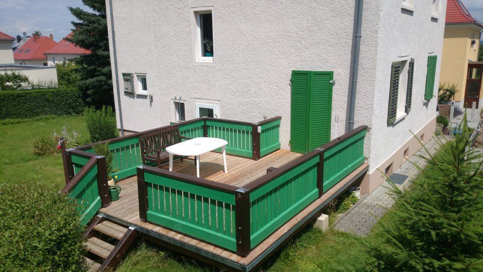 Haus mit Holzterrasse mit Treppe in den Garten