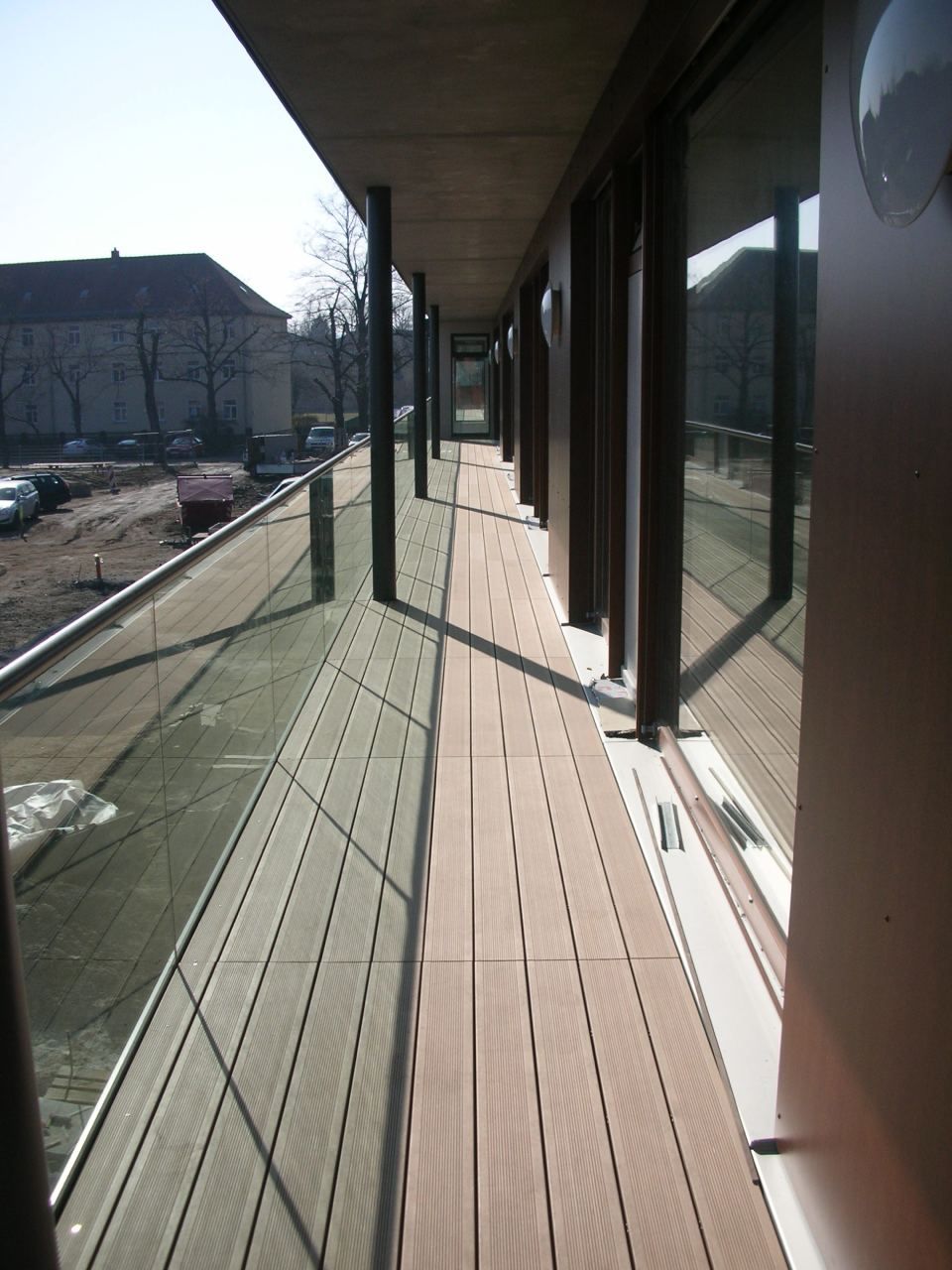 schmale Holzterrasse mit Glasgeländer