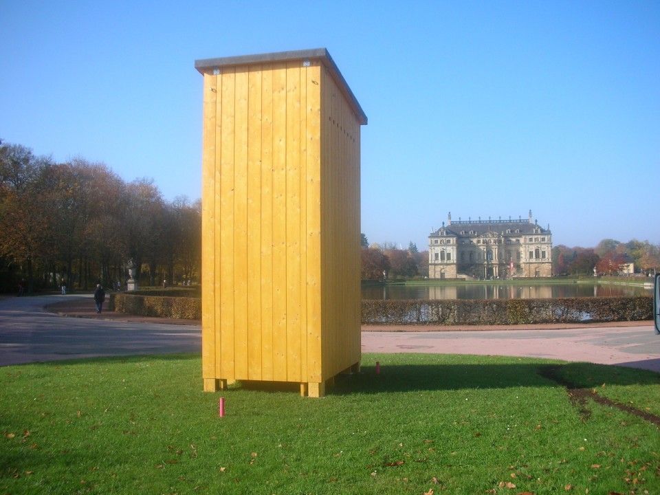 Spazierweg mit Blick auf herrschaftliches Gebäude und einem kleinen Holzhaus im Vordergrund
