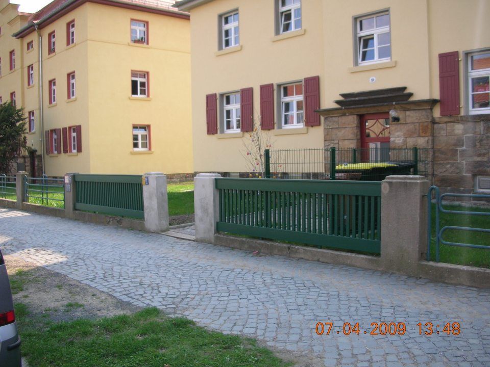 Wohnanlage mit grünem Holzgartenzaun