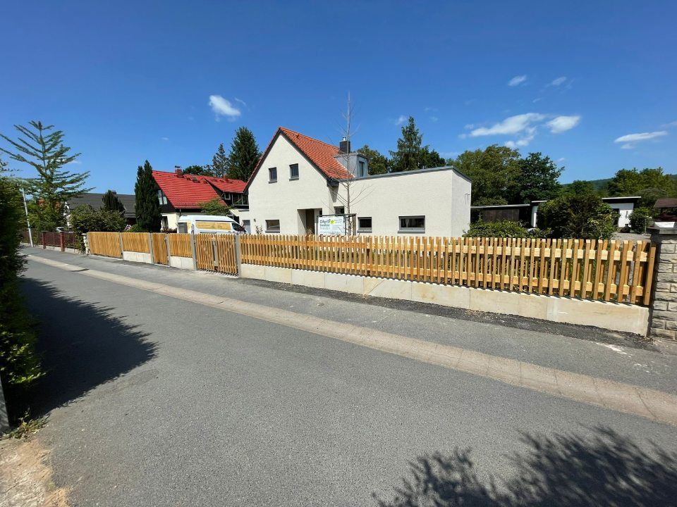 Mit einem Holzzaun eingezäuntes Familienhaus und Straße