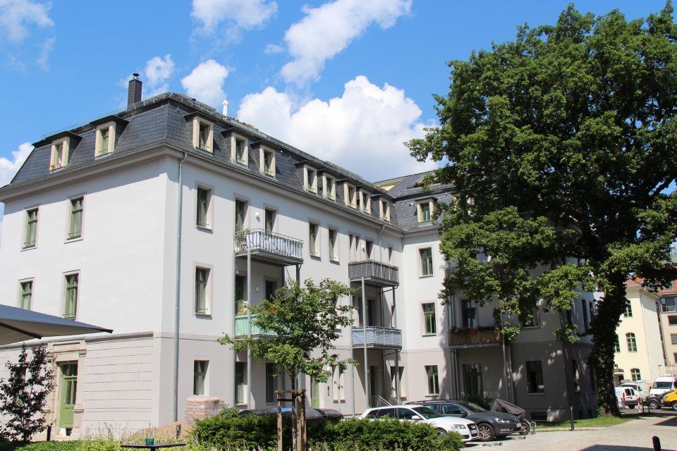 Weißes Mehrfamilienhaus mit sechs Holzbalkonen