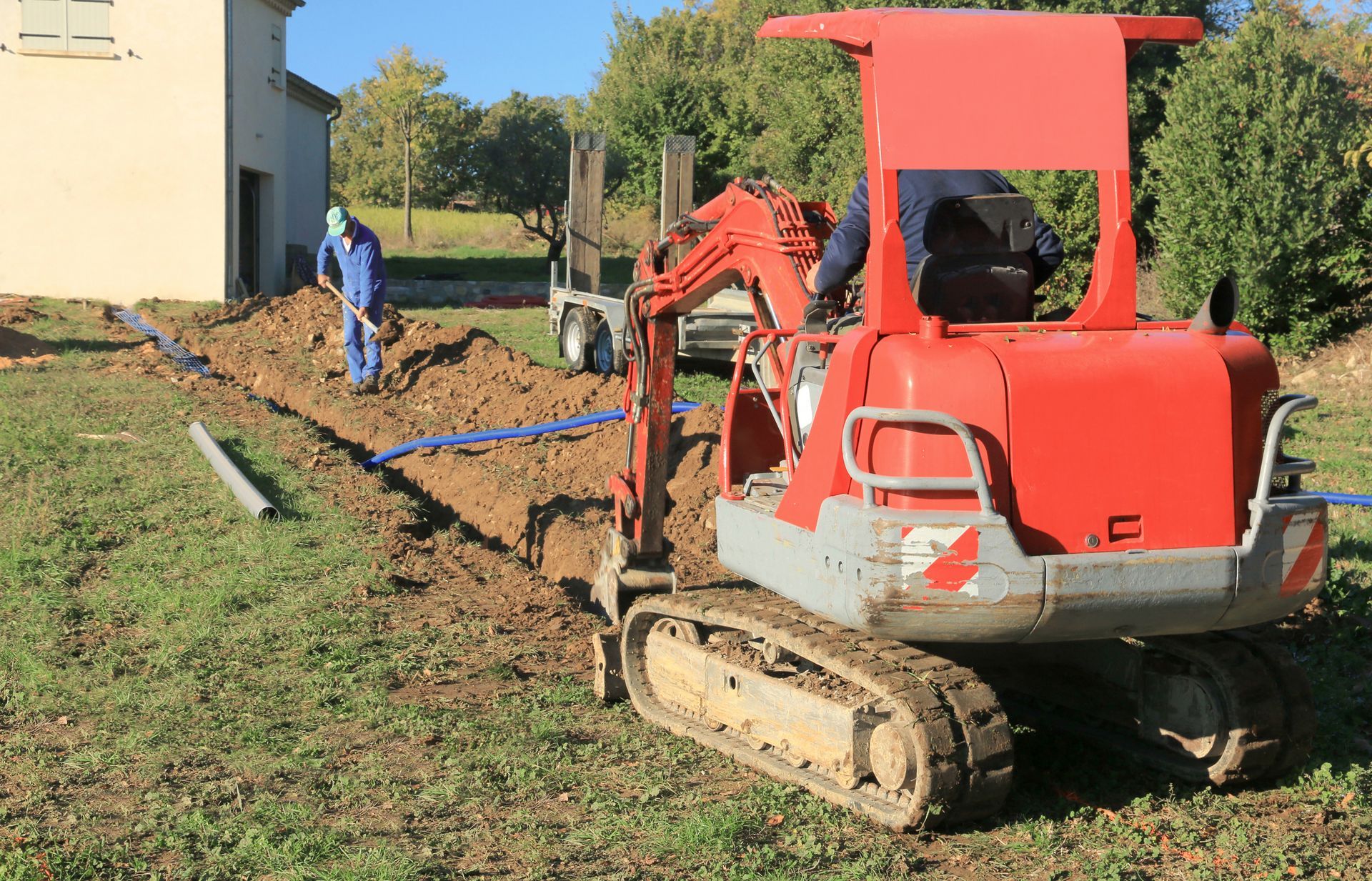 Minipelle creusant une tranchée pour un tuyau bleu