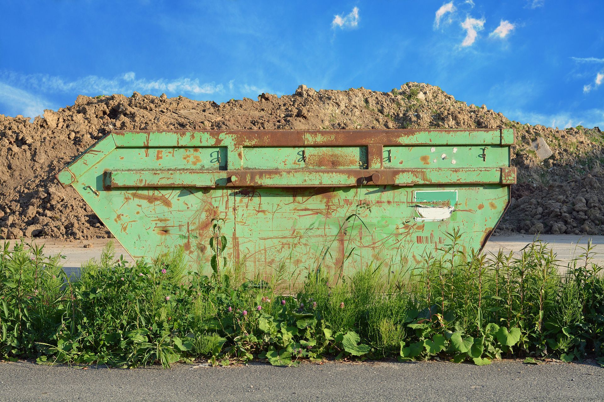 Benne à déchets devant une motte de terre