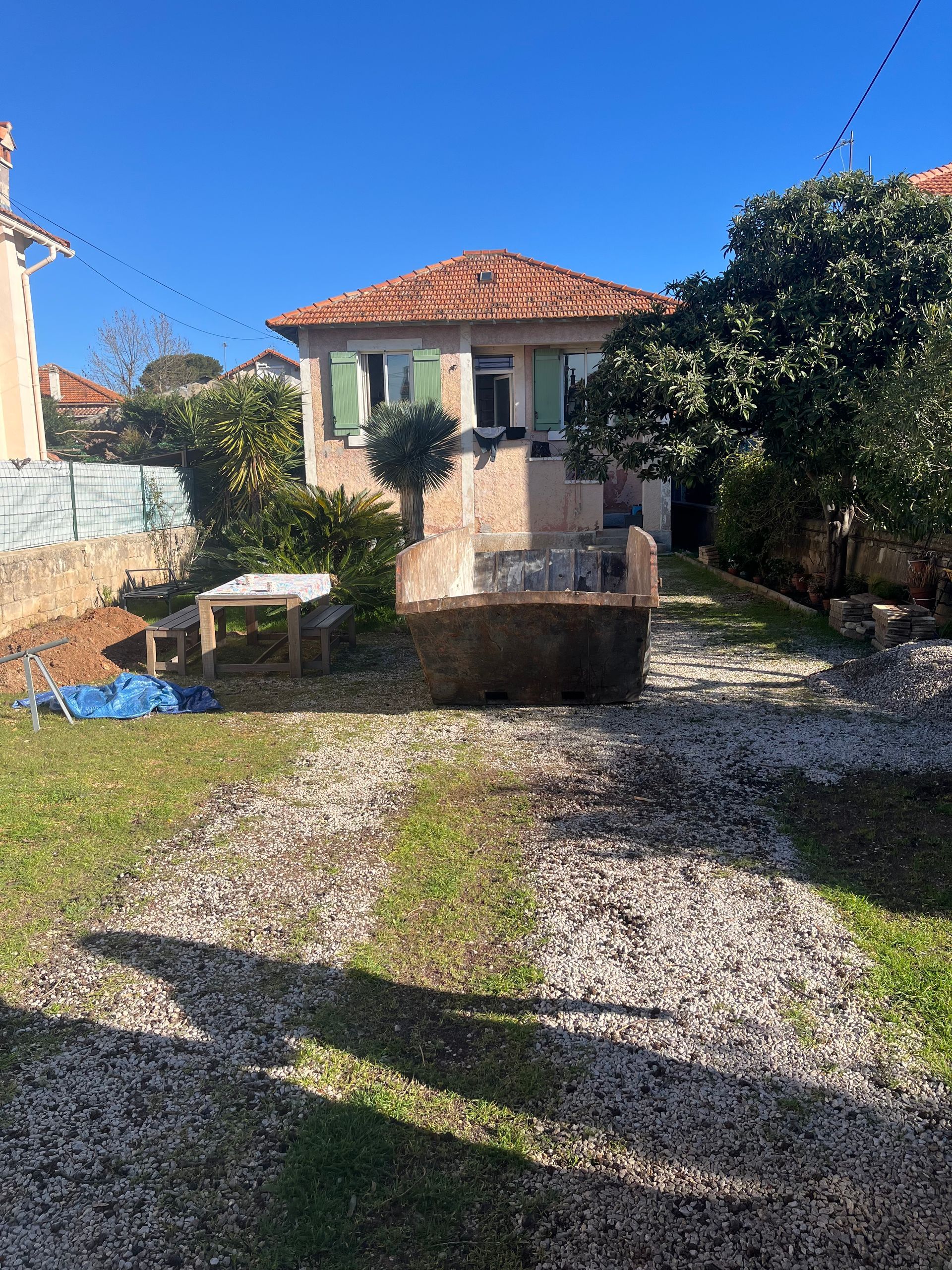 Benne à tout-venant posée dans un jardin