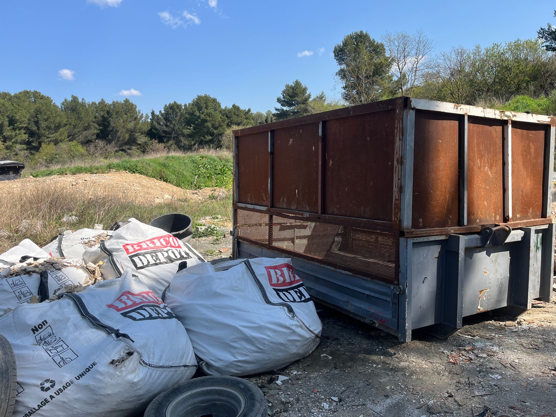 Un grand conteneur à déchets en métal rouillé