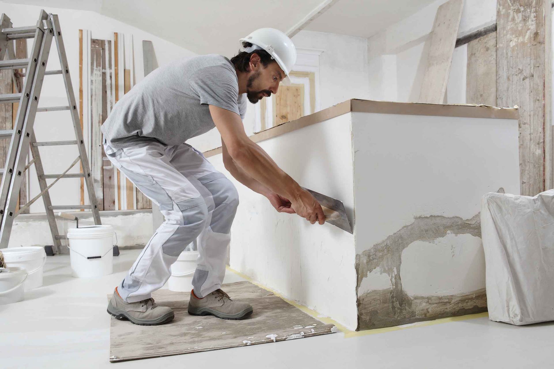 Un hombre está enyesando una pared con una espátula.