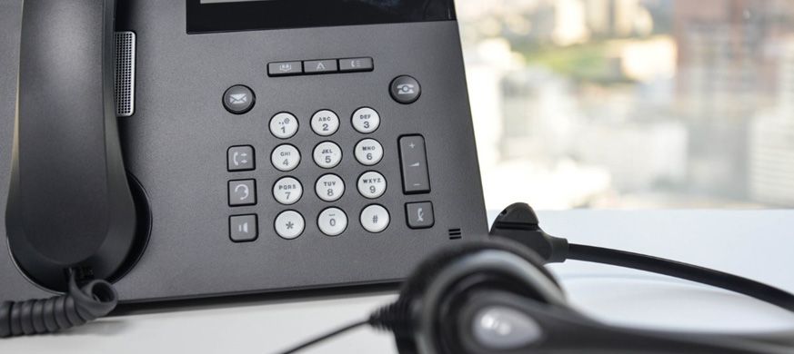 Un teléfono con un auricular conectado está sobre una mesa.