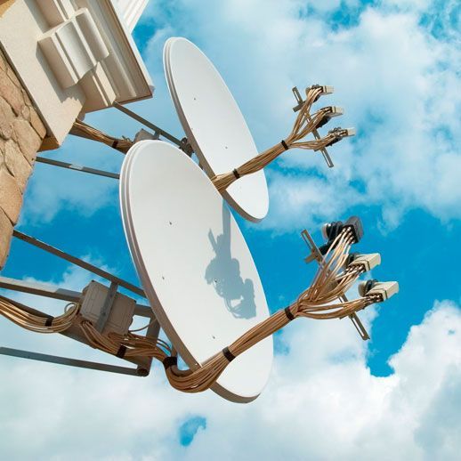 Dos antenas parabólicas conectadas a un edificio con un cielo azul de fondo