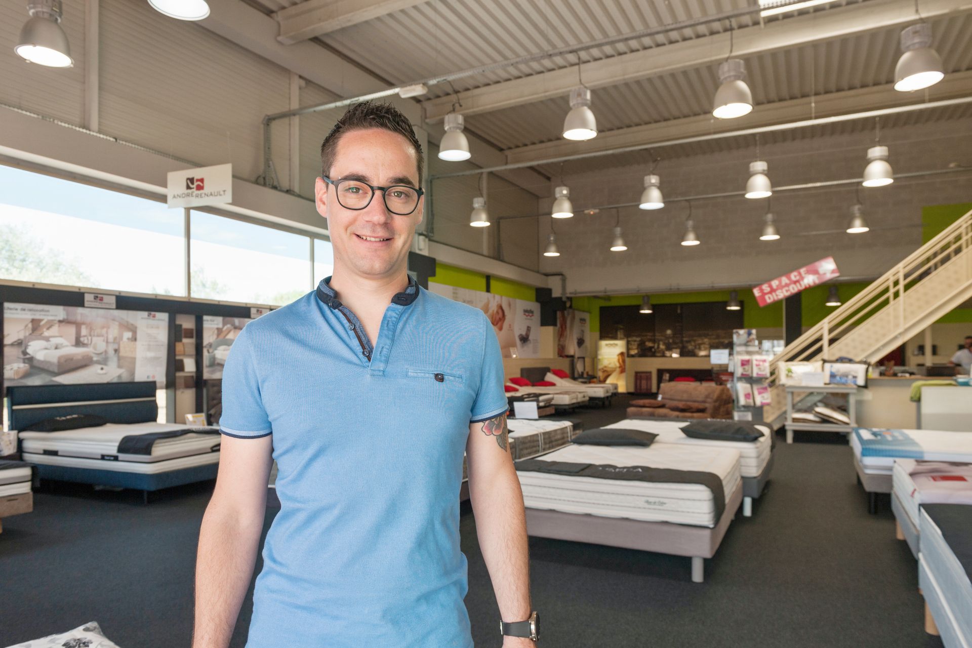 Le gérant devant l'intérieur du showroom du magasin Au Bonheur du Dormeur