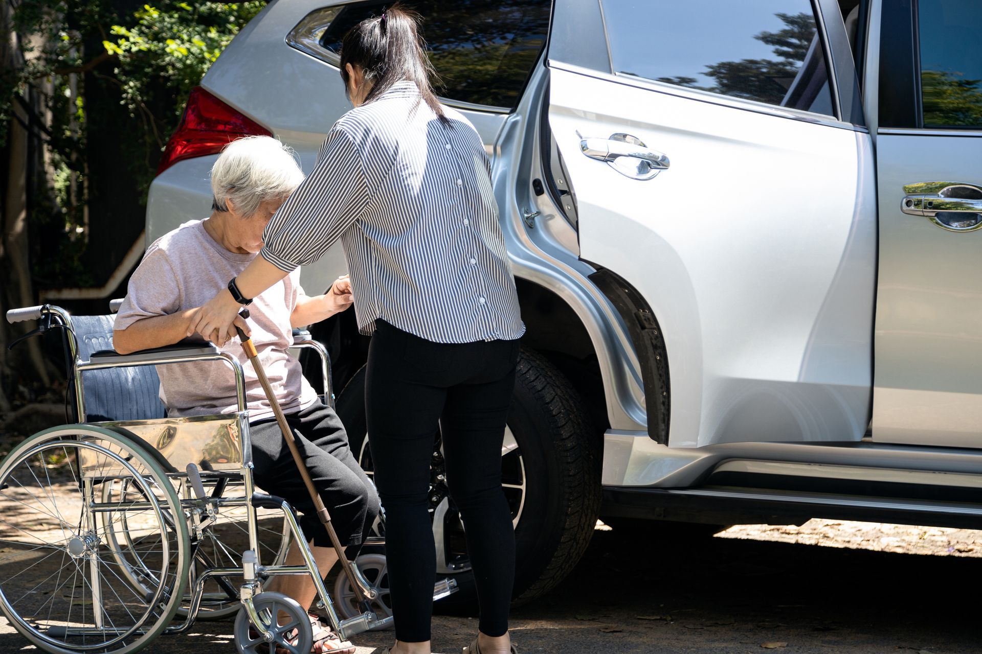 Une femme qui aide une personne âgée à monter dans la voiture.
