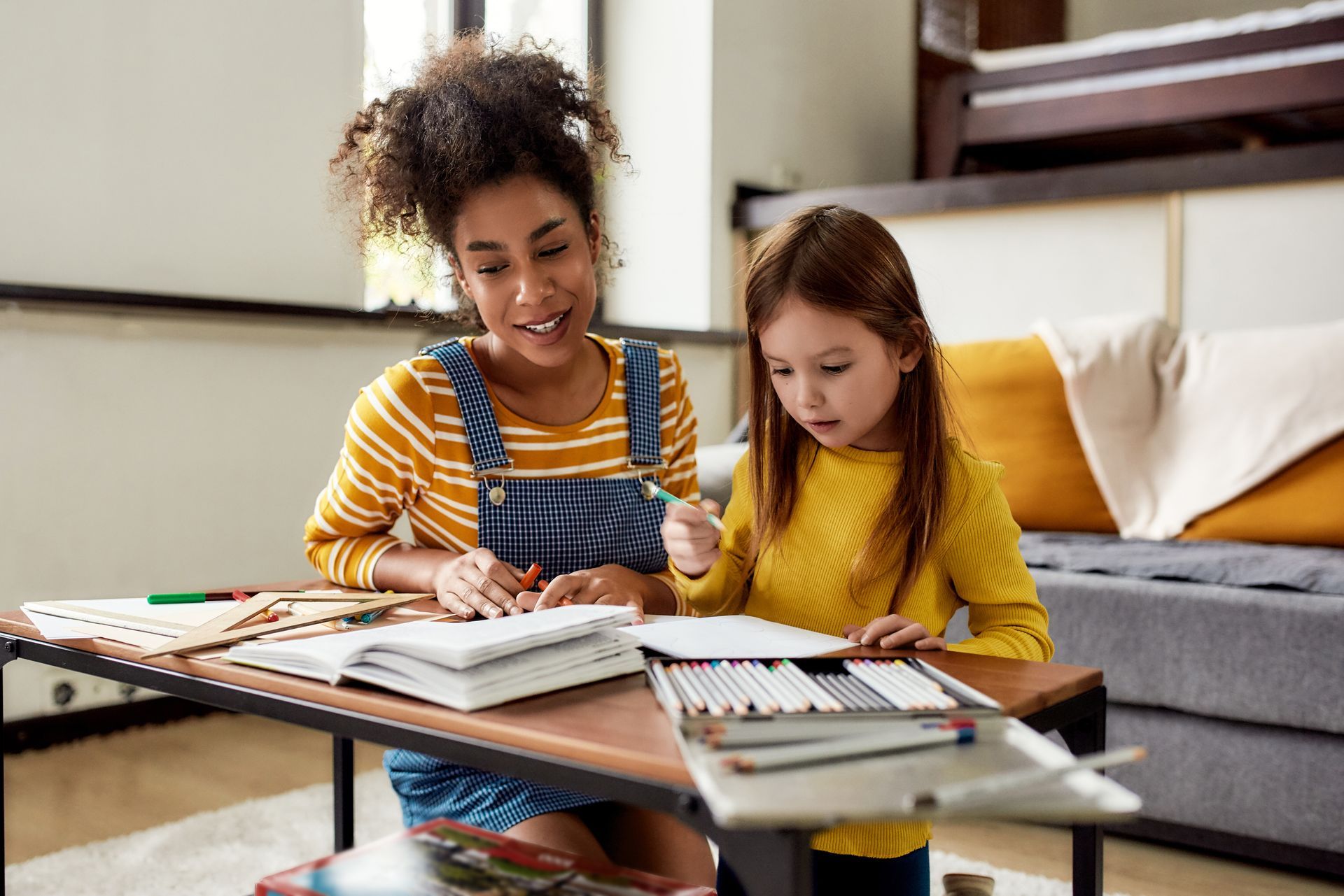 Une jeune femme qui aide une fille à faire ses devoirs.