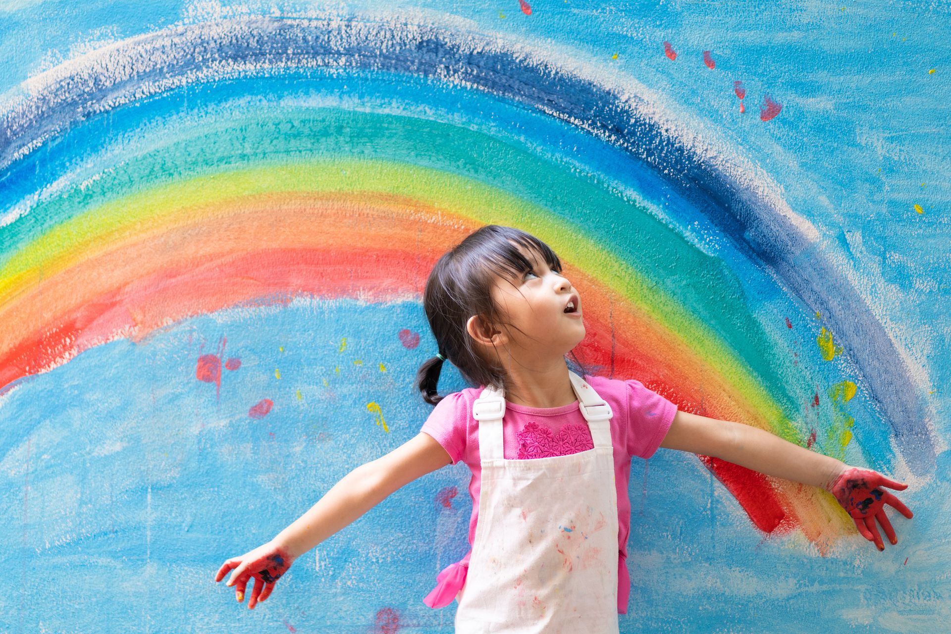 Une fille avec un arc-en-ciel en arrière-plan.