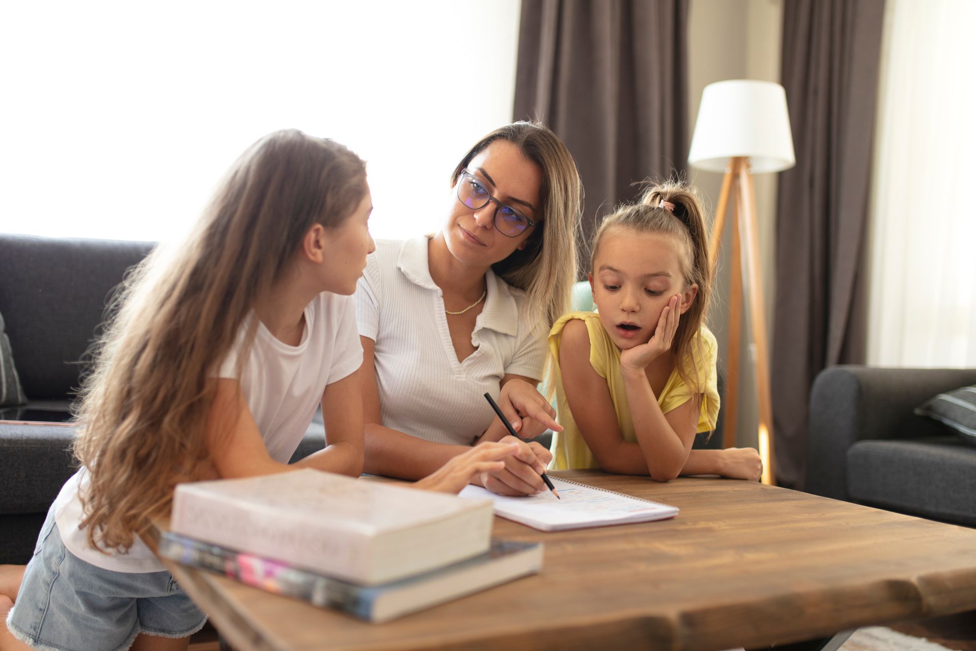 Une femme qui aide deux filles dans leurs devoirs.