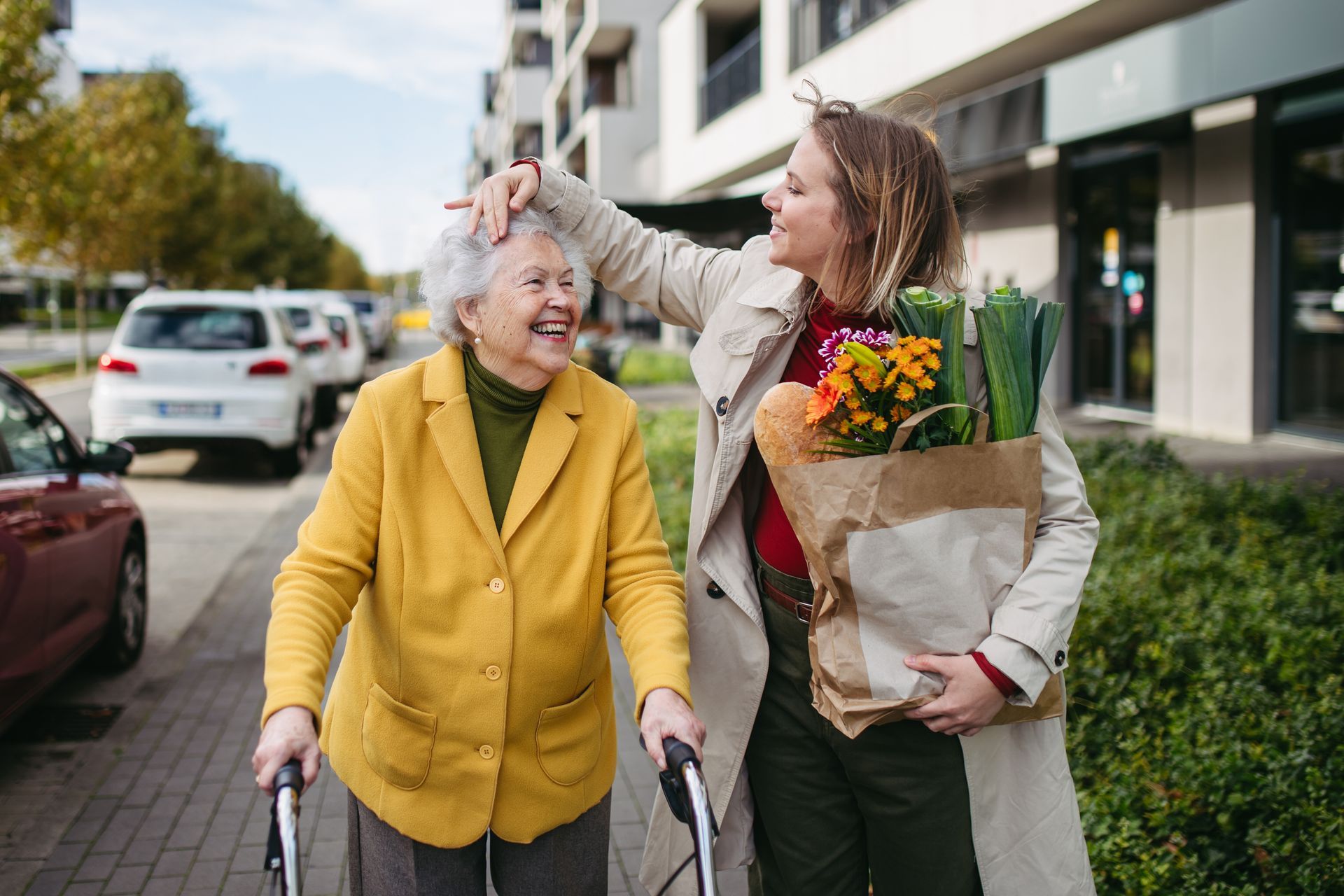 Une jeune femme accompagne une femme âgée avec un déambulateur.