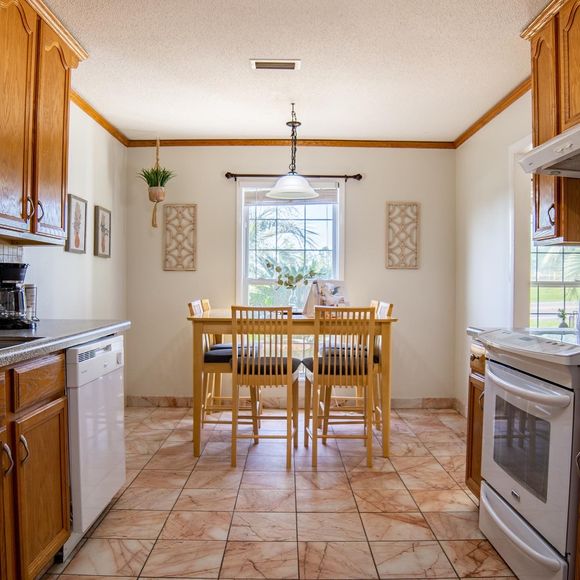 Bright kitchen with a wooden dining table, white appliances, and tiled floor