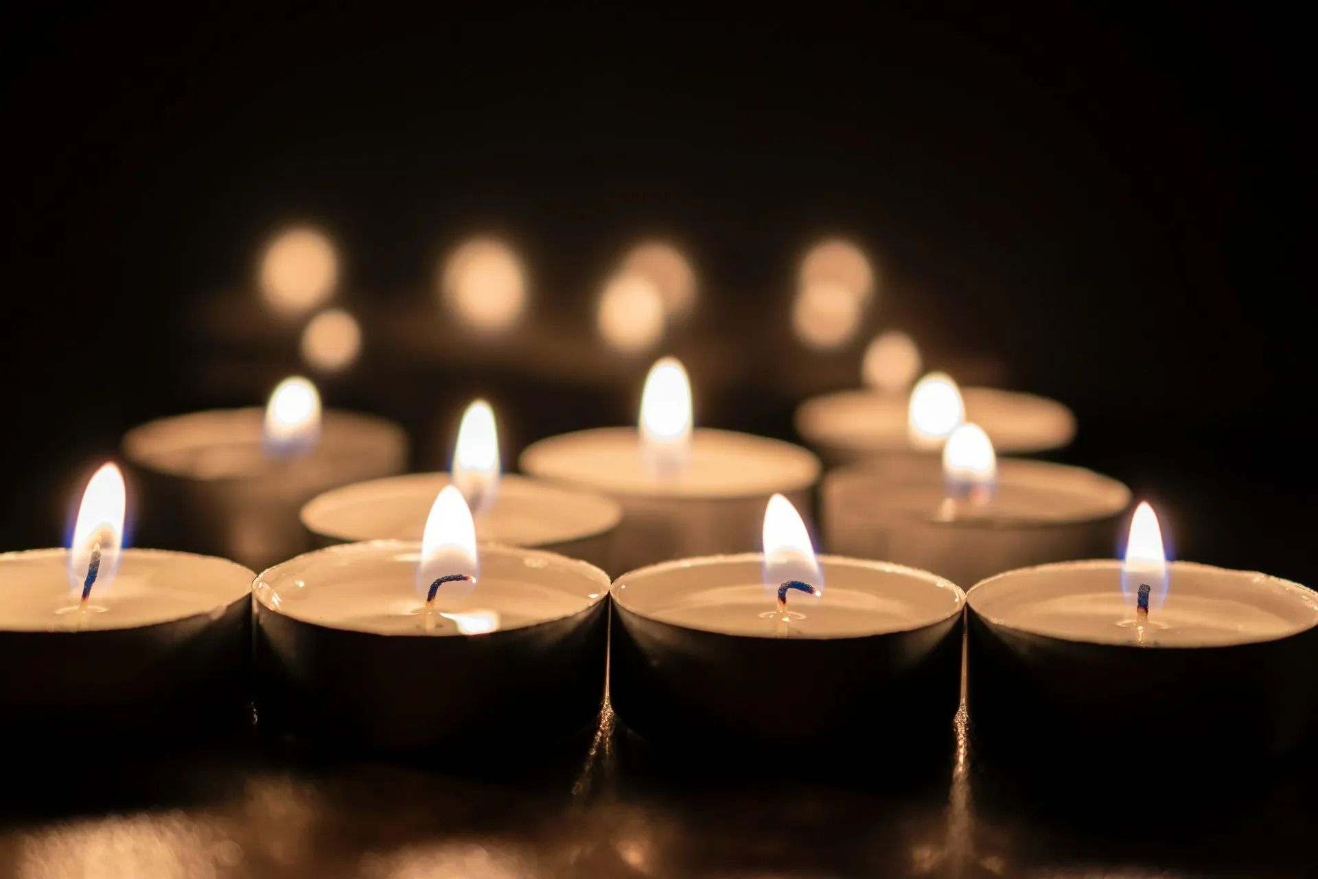 Des bougies chauffe-plat allumées dans l'obscurité, les flammes rougeoyantes.