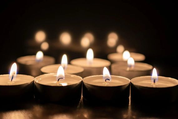 Des bougies chauffe-plat allumées dans l'obscurité, les flammes rougeoyantes.