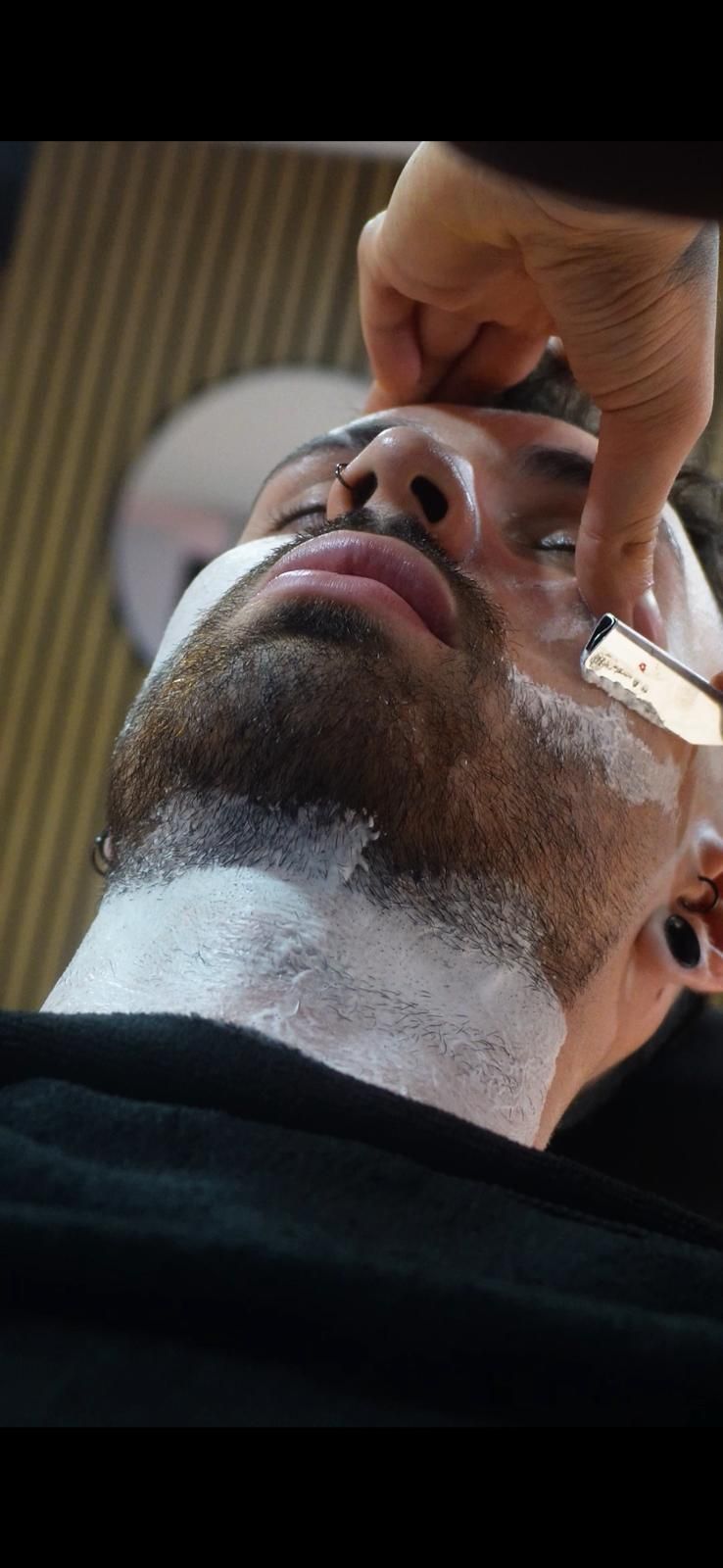 Hombre con un corte de pelo mullet rizado, con un desvanecimiento bajo en los lados, en un salón de belleza.